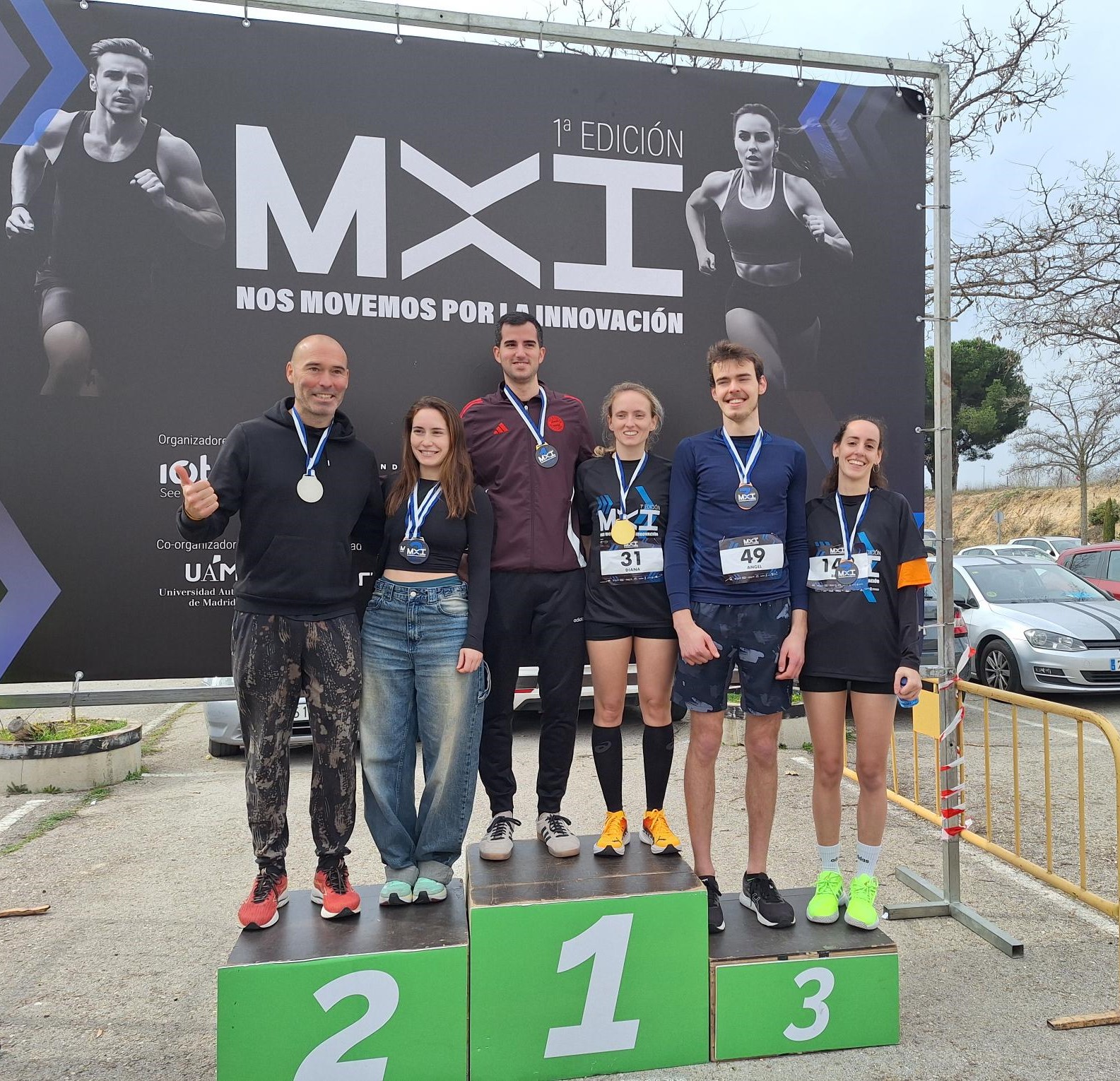 Podio de la I Carrera MxI. Primer puesto: Jorge Sarmiento (CBMSO) y Diana Tejerina (Fund. Novagob). Segundo puesto: Enrique Girón (Fuenla Joven) y Andrea Modrego (CNB). Tercer puesto: Ángel Quiles (UAM) y Belén Martínez (Grupo ClarkeModet).